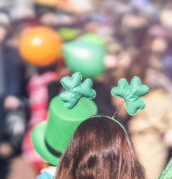 Clover head decoration on head of girl close-up. Saint Patricks day, parade in the city, selectriv focus, copy space